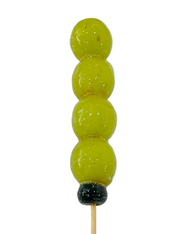 Green grape tanghulu skewer in a clear crystal glaze on a pale blue background